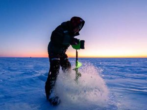 guide-peche-blanche-charles-dufour-roberval-ouananiche-dore-bateau le guide charles dufour perce des trous avec une tarière Ion G2 ice auger sur le lac saint jean pour pêcher le doré