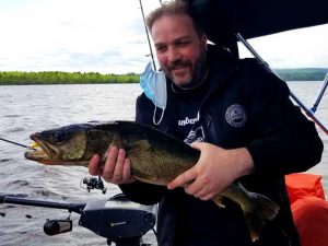 peche-dore-jaune-lac-saint-jean-guide-bateau gros doré jaune remis à l'eau au saguenay lac saint jean avec technique de pêche a la jig la réglementation en vigueur, belle capture d'un client heureux a bord du bateau de aventure lac saint jean