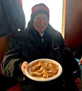degustation-poisson-shore-lunch-personne-agé-guide-peche pendant un belle journée de pêche blanche sur la glace, ce que notre guide de pêche charles dufour aime le plus c'est de cuisiner un bon repas shore lunch de poisson doré directement sur la glace dans la cabane a pêche lors d'un forfait de pêche