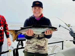 femme-capture-poisson-peche-quebec-ouananiche-lacsaintjean belle ouananiche capturé par une cliente de aventure lac st jean qui est une super bonne pêcheuse Pêche avec ligne plombé à la ouananiche et sonar garmin avec guide de pêche charles dufour au québec canada saguenay lac st jean
