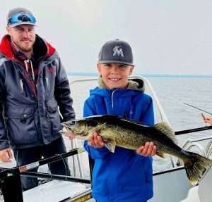 guide-peche-enfant-gros-doré-lac-st-jean-activité-famille La pêche en bateau sur les eaux du lac st jean est une superbe activité en famille avec les enfants. Voici le jeune pêcheur Jacob qui a capturé un beau doré jaune avec sa canne à pêche accompagnée du guide de pêche charles dufour